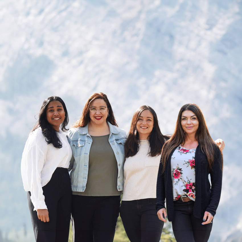 four women stand in front of a mountain