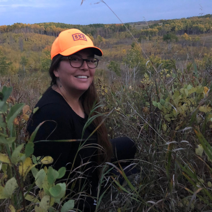 Indigenous advisor Kerry sitting in a field, wearing a yellow hat