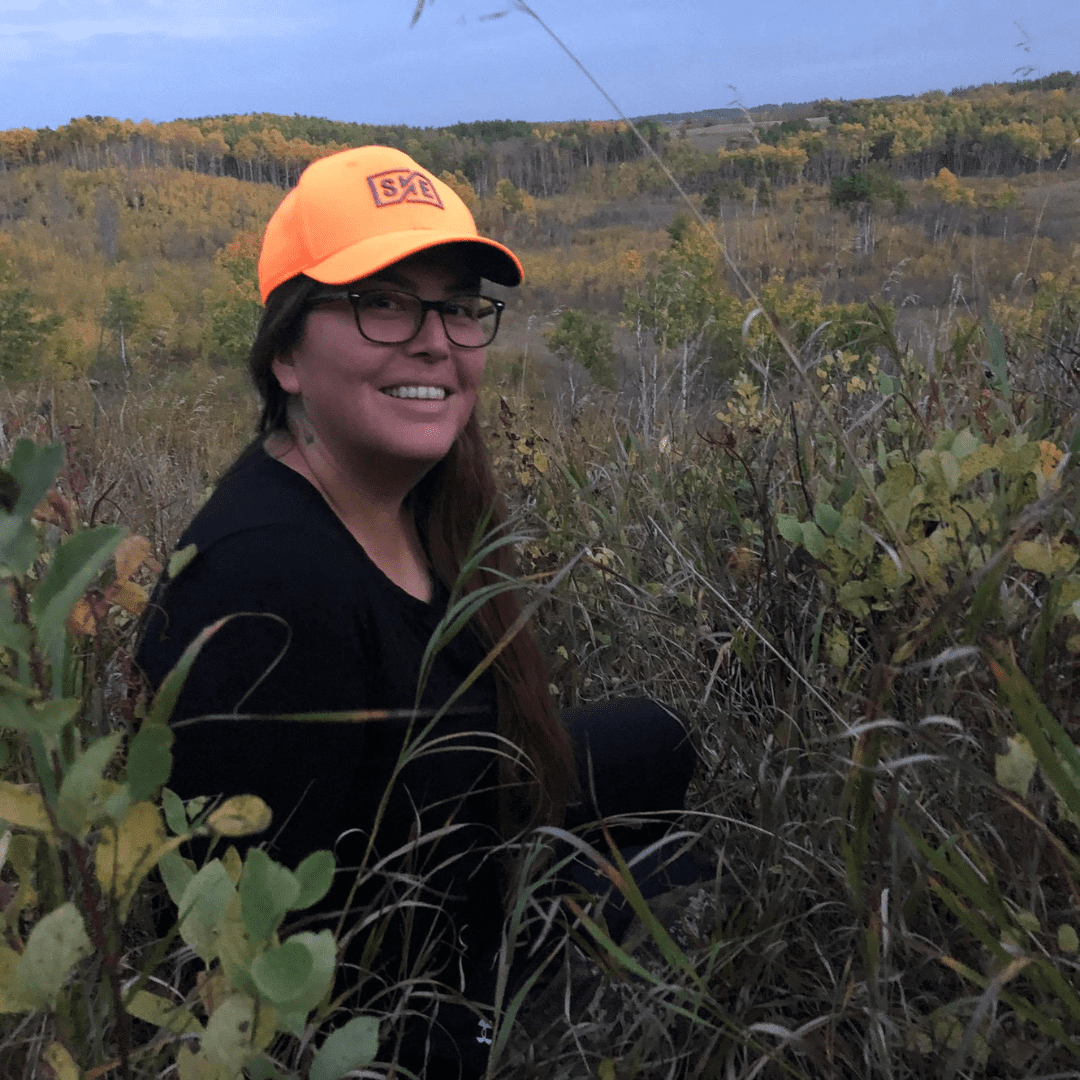 Indigenous advisor Kerry sitting in a field, wearing a yellow hat