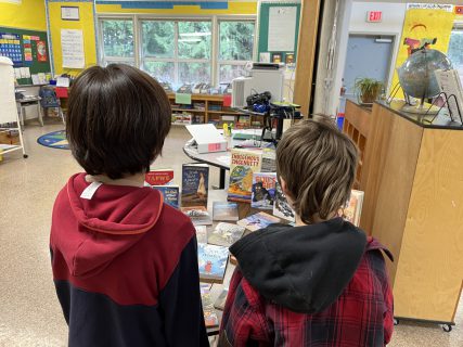 Two young boys looking at a collection of indigenous books