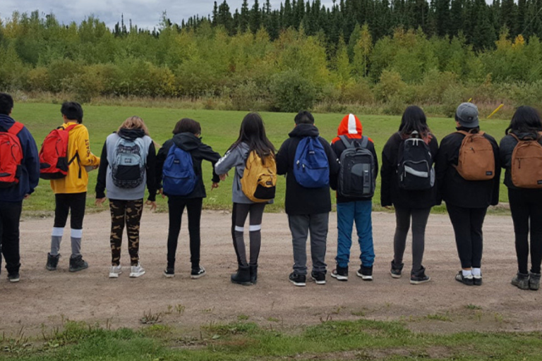 backpacks Deer Lake students with their backs facing camera, wearing their backpacks