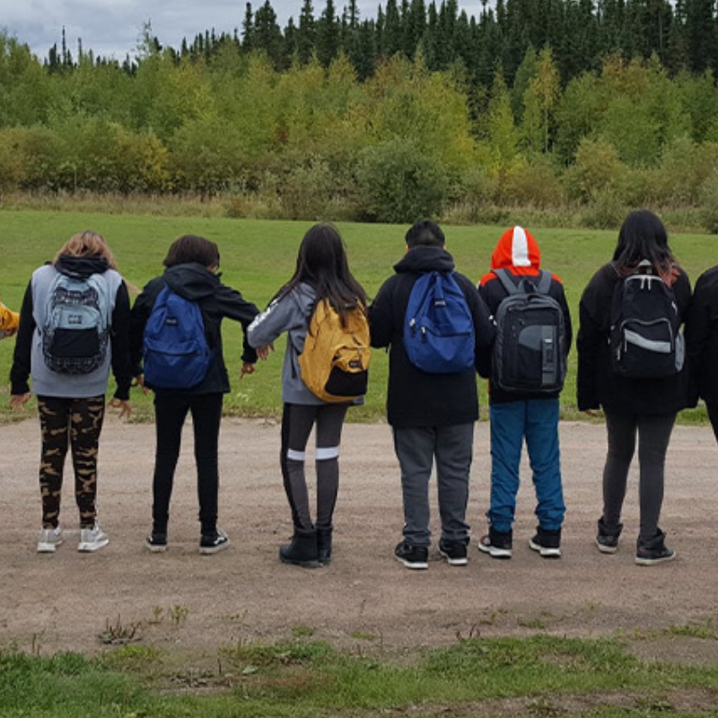 students with their backs facing camera, wearing their backpacks