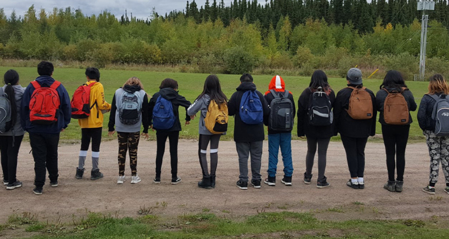 students with their backs facing camera, wearing their backpacks
